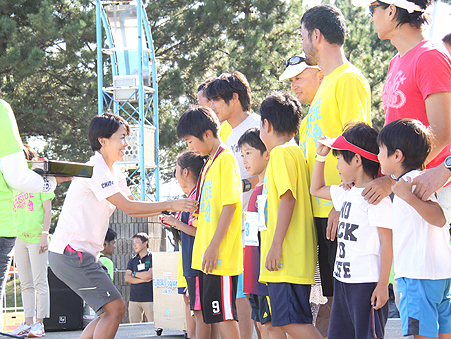 Ms. Ueda handing medals to children at Yokohama Seaside Triathlon (September 29, 2013)